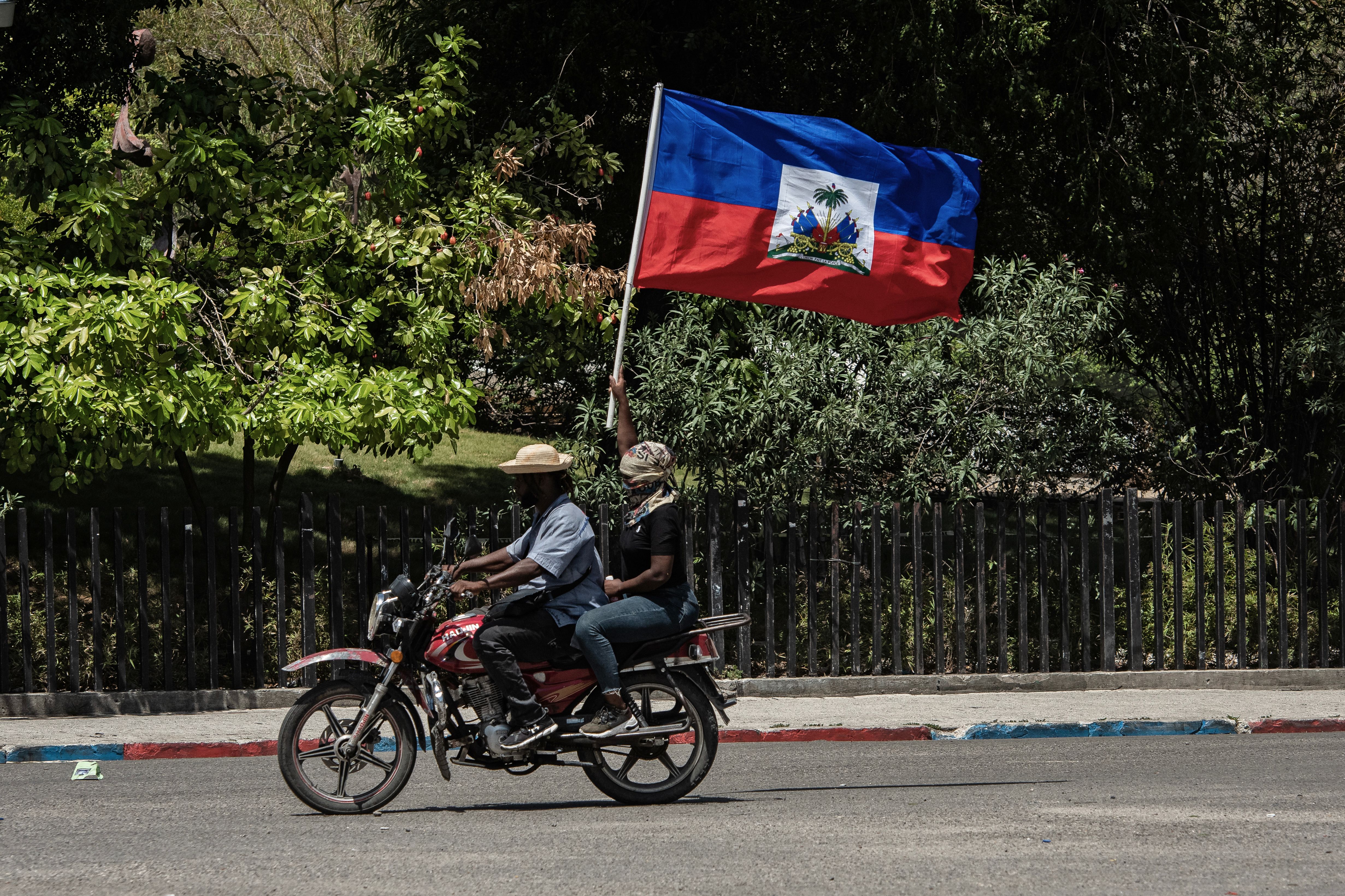 Dans le centre ville, une femme porte le drapeau haïtien lors d’une manifestation qui dénonce l’insécurité et appelle les autorités à agir plus fermement contre les gangs. 