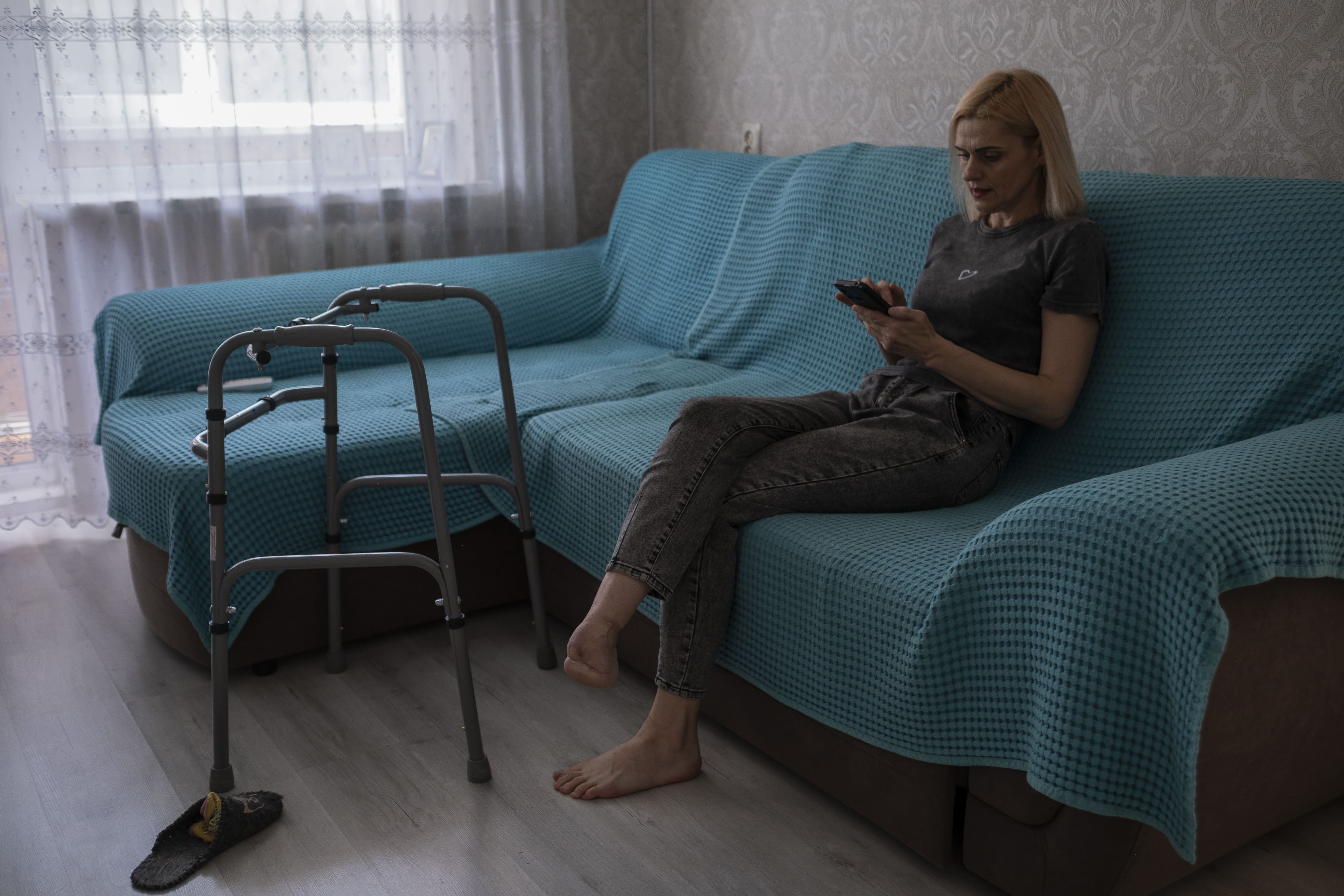 Olena est sur son téléphone dans le salon de l’appartement qu’elle loue à une amie partie à l’étranger, le 4 août 2025 à Kherson.