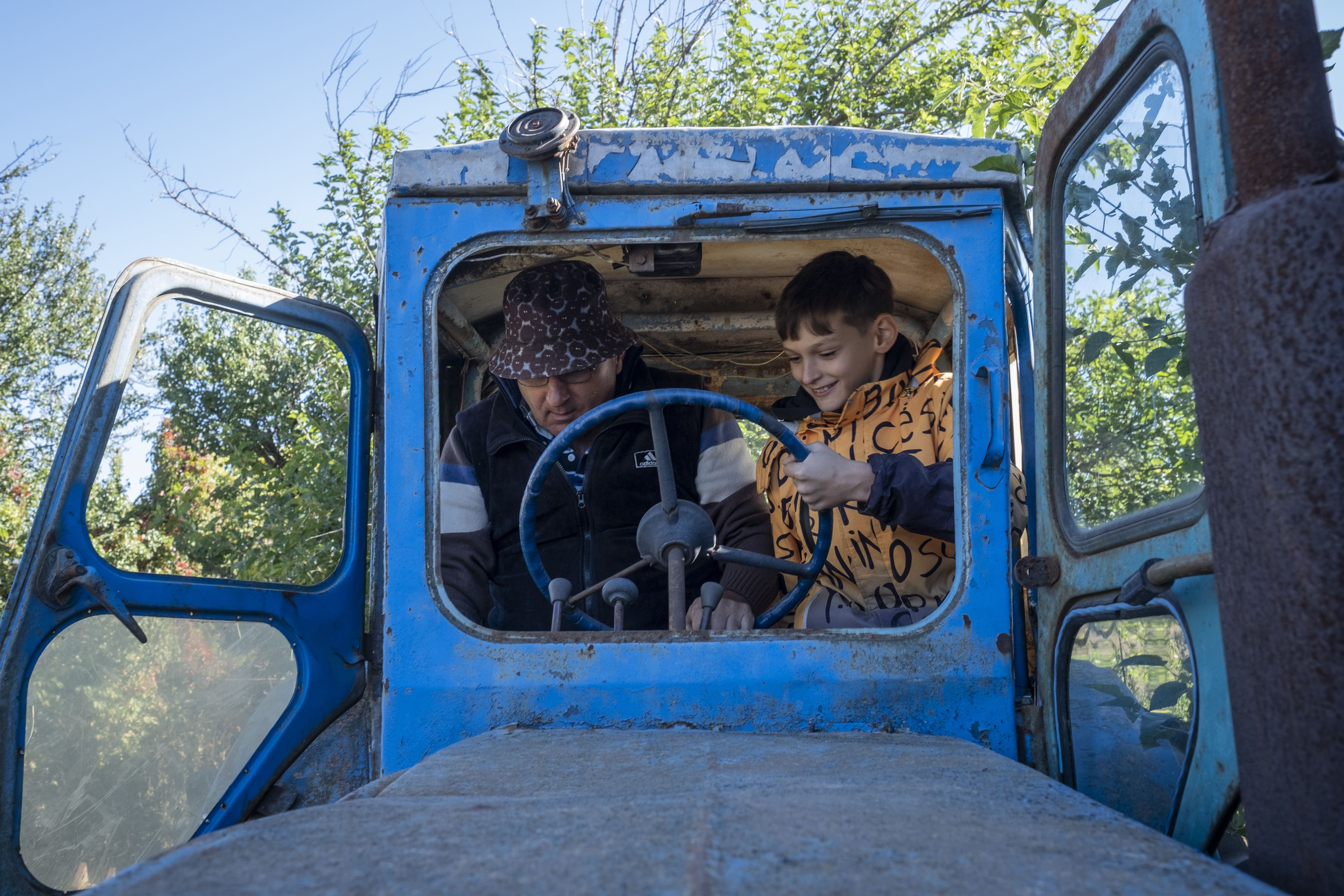 Sergii, accompagné de  Bogdan, vérifie si le moteur de son tracteur fonctionne encore, le 25 septembre 2025.