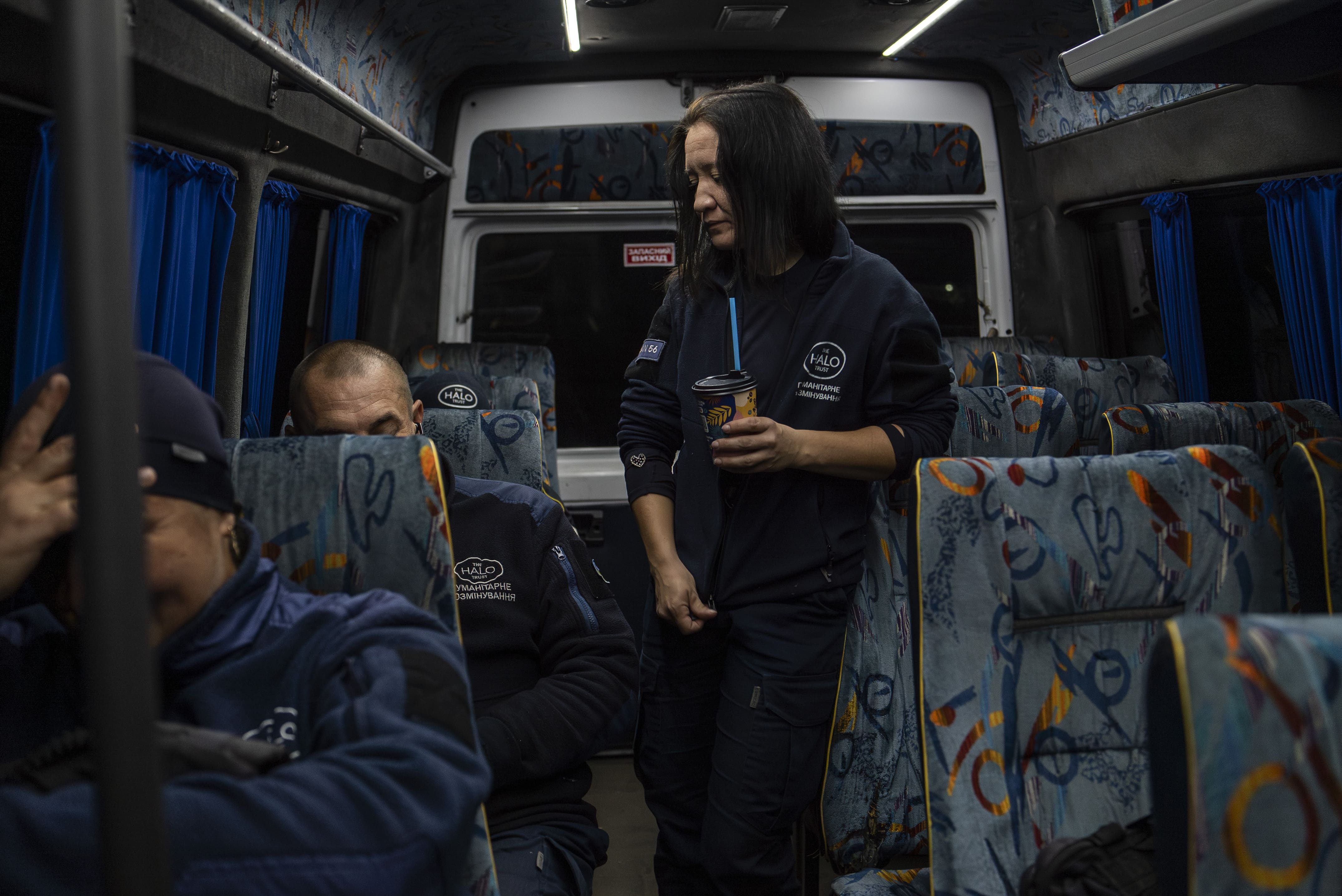 Lyza discute avec ses collègues dans le minibus qui les emmène au deuxième point de rendez-vous pour prendre une autre navette vers leur lieu de travail, le 24 octobre 2025.