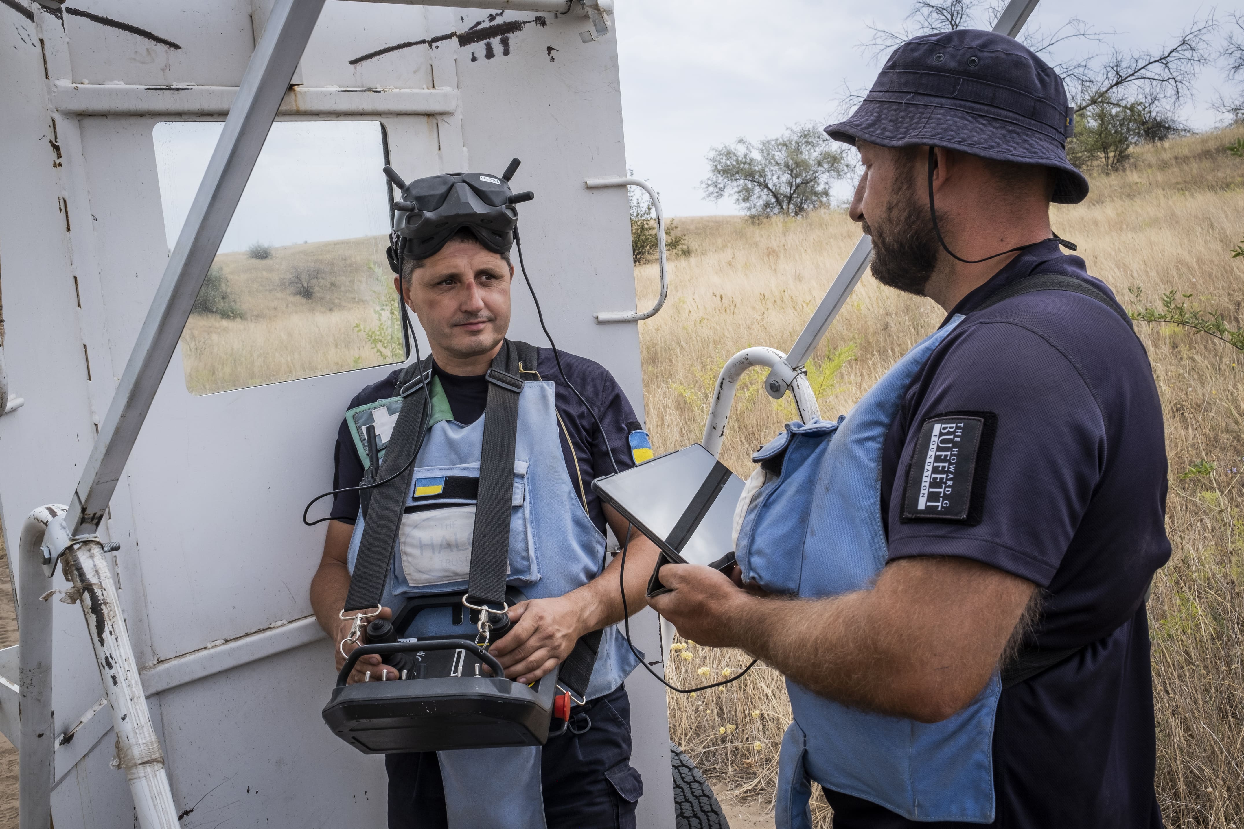 Des membres de l’équipe mécanique de HALO préparent le terrain avec une machine PT300 avant de passer avec une chargeuse compacte pour le déblaiement et la préparation de la zone pour le déminage manuel, le 11 août 2025.