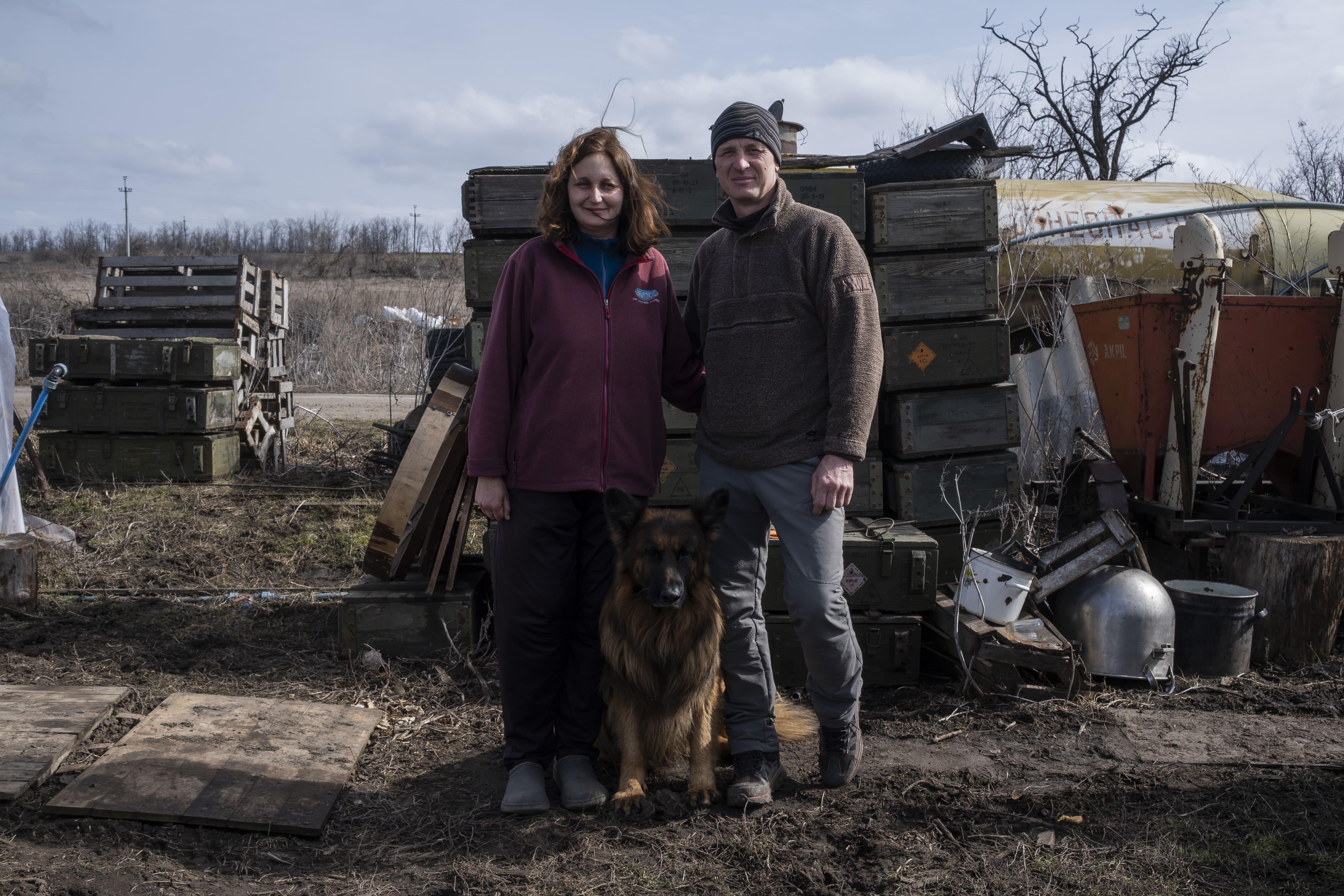 Liudmila et Volodymyr posent dans la cour de leur ferme avec leur chien, le 16 mars 2026. 