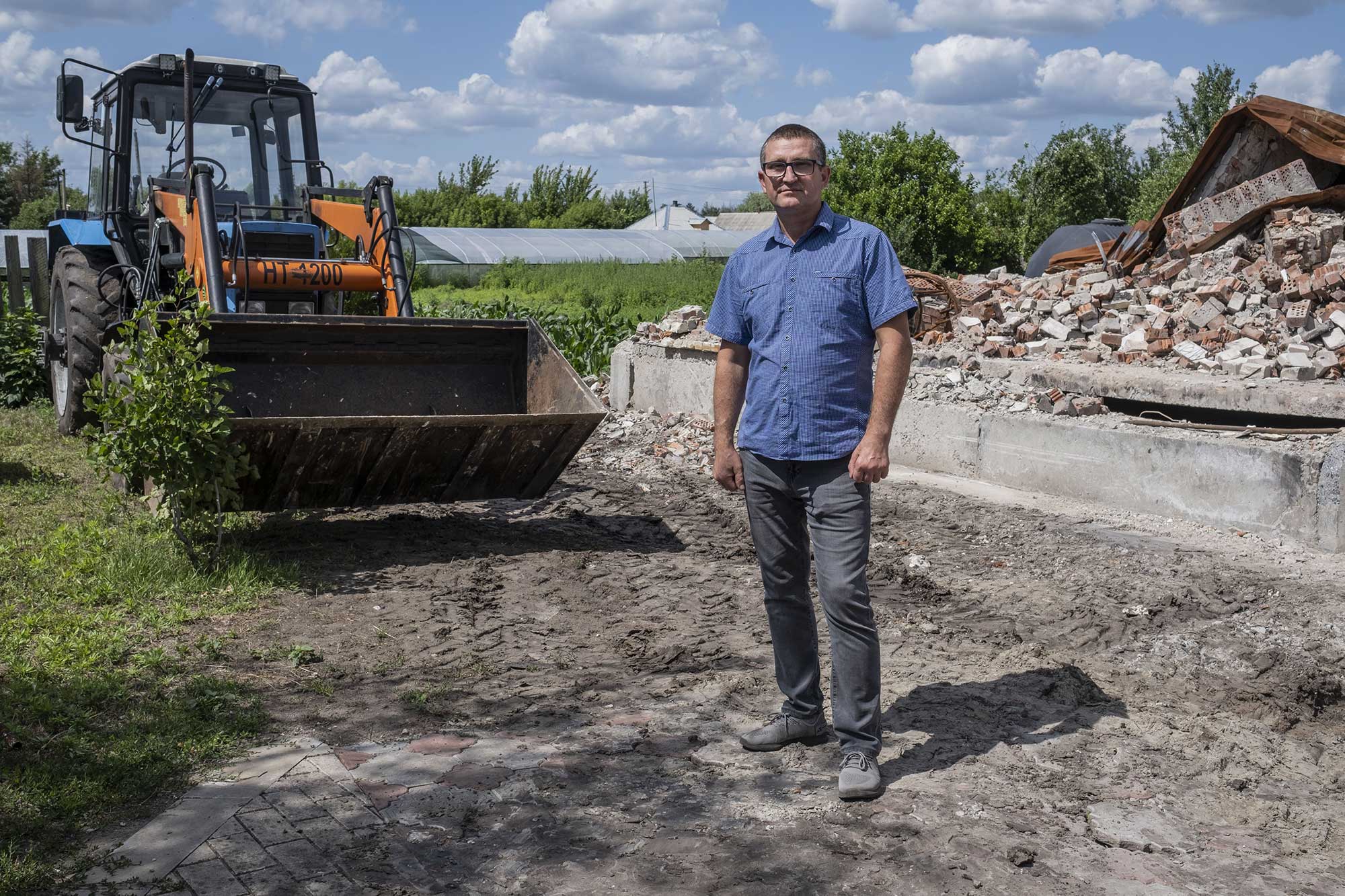 Sergii Kohan, 49 ans, pose devant les ruines de sa maison et un tracteur qu’il a emprunté à un ami, le 30 juin 2025.